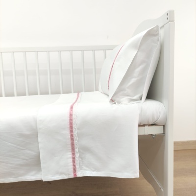 Cama branca com lençóis e fronha brancos com linha vermelha