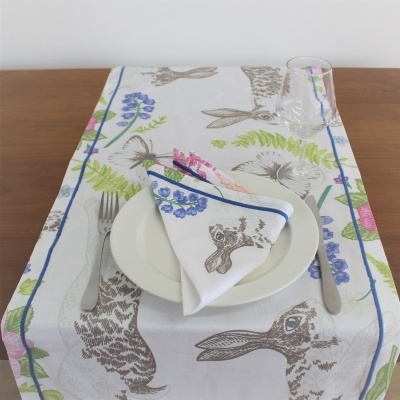 Lugar de refeição com toalha e guardanapo com estampas de coelhos e flores, prato branco, talheres e copo