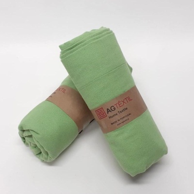 Tecidos verdes enrolados com etiquetas AGTÊXTIL Home Textile