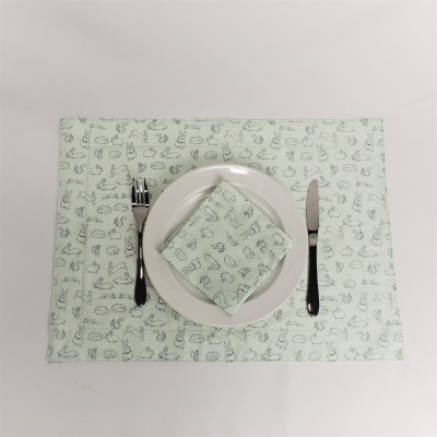 Jogo americano e guardanapo verdes com estampado, prato branco, talheres