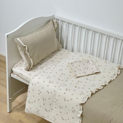 Berço branco com roupa de cama bege e creme com padrão de flores pequenas.
