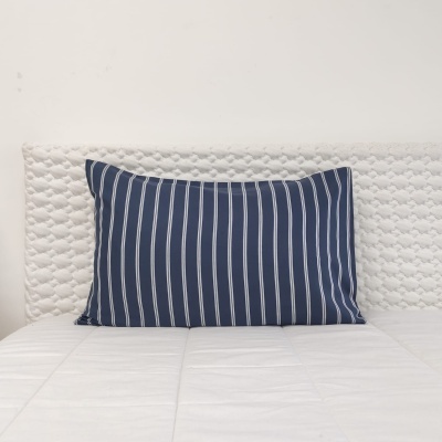 Travesseiro azul com riscas brancas sobre cama branca