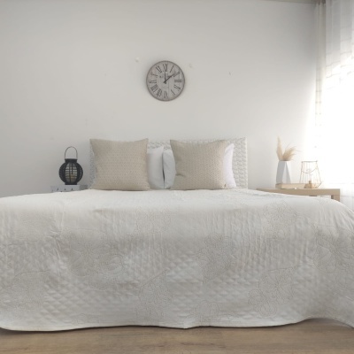 Cama com colcha branca, almofadas e decoração minimalista