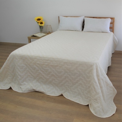 Cama de casal com colcha branca texturizada e almofadas brancas