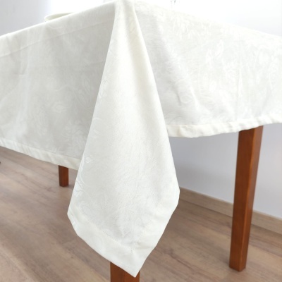 Toalha de mesa branca com padrão floral em relevo sobre mesa de madeira