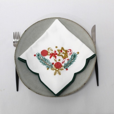 Guardanapo branco bordado com motivos natalícios sobre prato cinzento com talheres