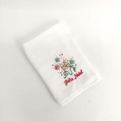 Toalha branca com bordado natalício e texto 'Feliz Natal'.
