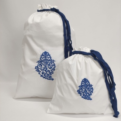 Duas bolsas de tecido branco com cordões azuis e padrão azul bordado