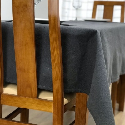 Mesa de madeira com toalha preta e cadeiras de madeira clara em interior