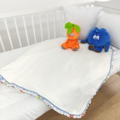 Cama de bebé com edredom branco, almofadas e peluches coloridos