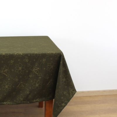 Toalha de mesa verde-oliva com padrão decorativo numa mesa de madeira
