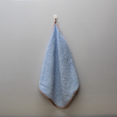 Toalha azul claro com borda castanha pendurada num gancho branco