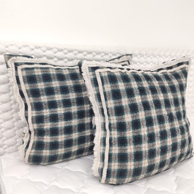 Duas almofadas quadradas xadrez azul e branco sobre colchão branco matelassado