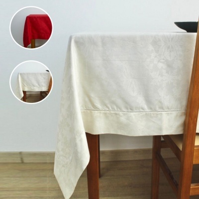 Toalha de mesa branca com padrão floral em relevo e costura decorativa num ambiente com mesa de madeira