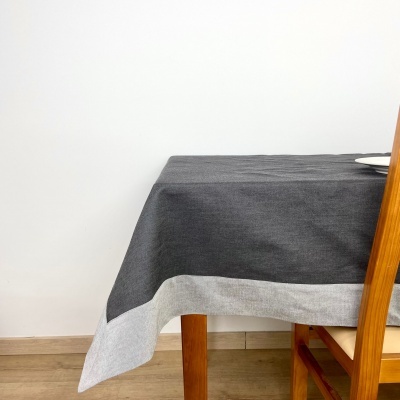 Toalha de mesa preta com borda cinza sobre mesa e cadeira de madeira