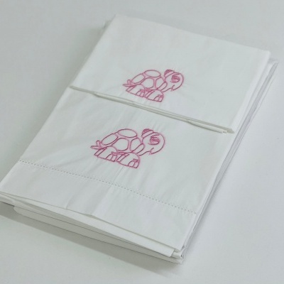 Conjunto de roupa de cama branca com bordado rosa de tartarugas.