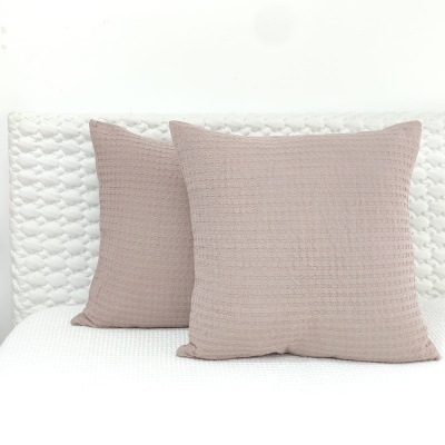 Duas almofadas cor de rosa claro com textura quadrada sobre capa branca texturada
