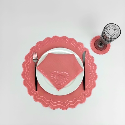 Conjunto de jantar com placa, guardanapo, talheres e copo em branco e coral.