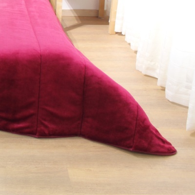 Cama com edredão de veludo vermelho vinho perto de cortinas brancas