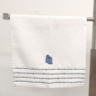 Toalha branca com bordado azul e padrão de linhas e pontos azuis