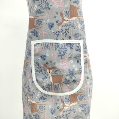 Avental cinza com padrão de cervos e folhas, com bolso branco frontal
