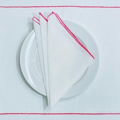 Guardanapo e individual branco com borda vermelha sobre prato branco