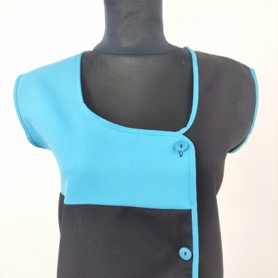 Top assimétrico preto e azul turquesa com dois botões na frente em manequim.