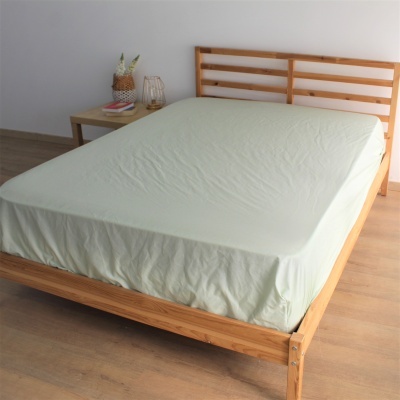 Cama de madeira clara com lençol verde claro em quarto minimalista