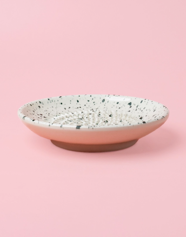 PRATO RALADOR PEQUENO "GRANITO" ALFAR TIERRA COCIDA Prato cerâmico branco com manchas negras e relevo, sobre fundo rosa