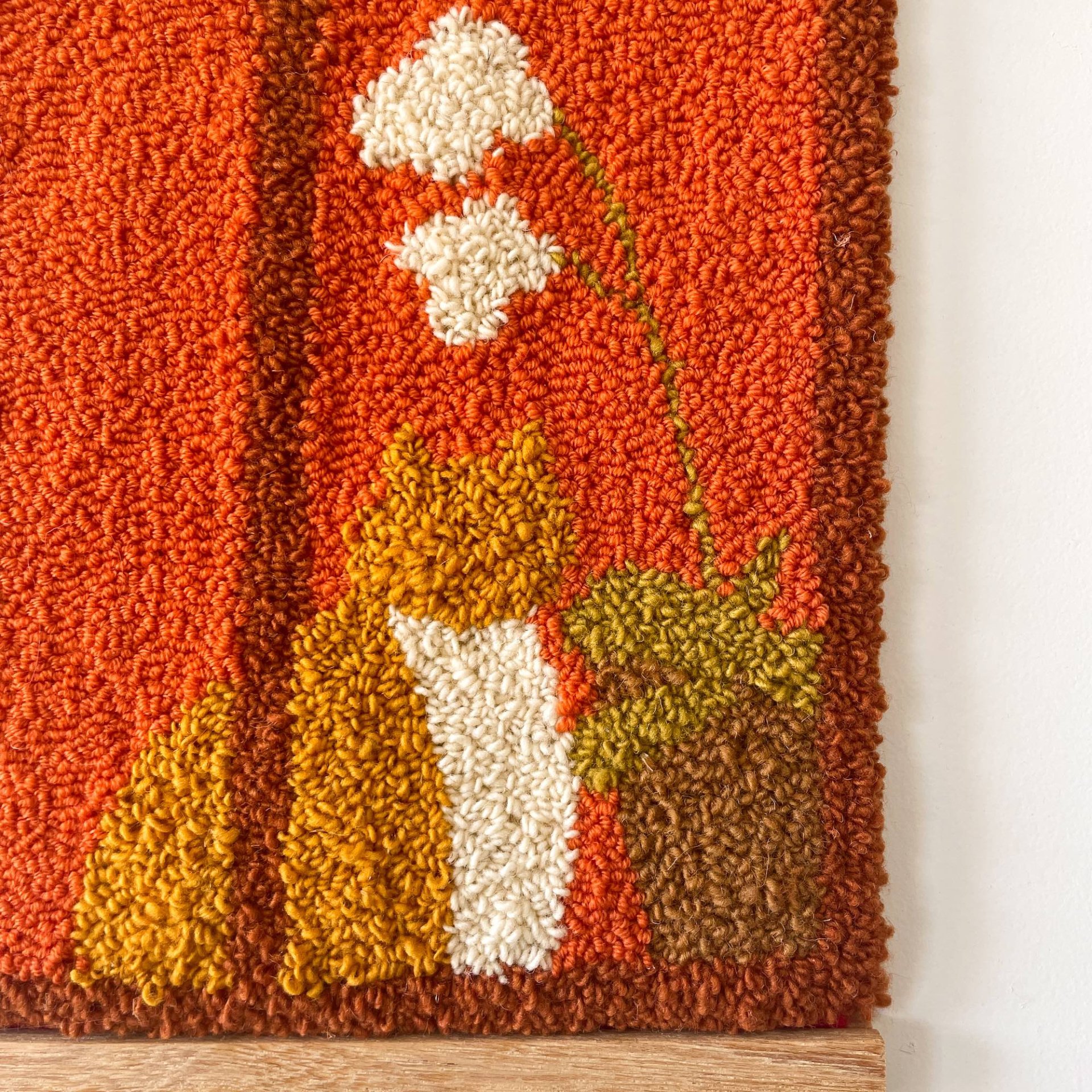 ORIGINAL "CARVALHIDO" SARA FELGUEIRAS Tapete de lã com padrão floral em cores quentes sobre chão de madeira.