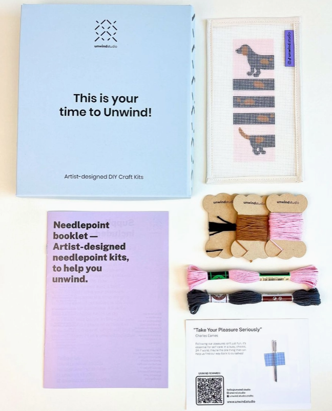 "WI(E)NNER BOOKMARK NEEDLE STICH KIT " UNWIND STUDIO Kit de ponto de agulha DIY com caixa azul, instruções lilás, bordado de cão, fios de bordar e cartão informativo.