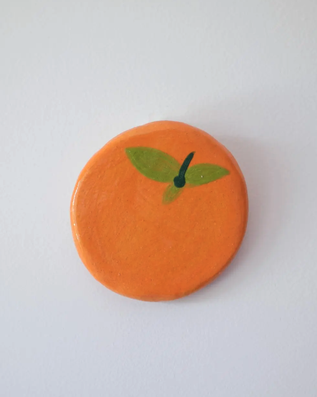 PEÇAS DE CERÂMICA "BREAKFAST FOR DINNER" KIKA Prato redondo de cerâmica pintado em laranja com folhas verdes.