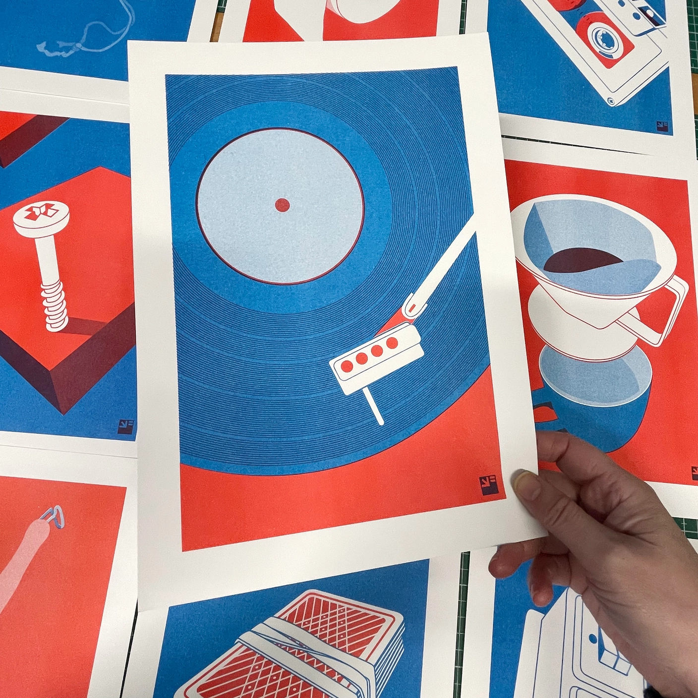 RISO PRINT -VINIL - EXTRAORDINÁRIO - A4 - VRIJFORMAAT Impressão artística colorida com gira-discos em azul e vermelho segurada por uma mão