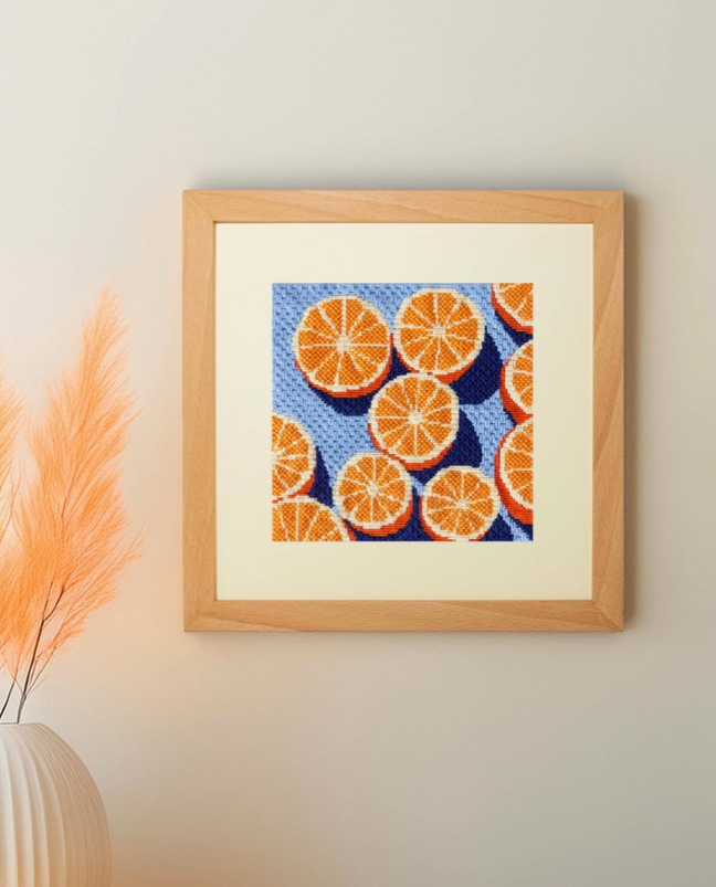 KIT DE PONTO CRUZ "AGRUMES" UNWIND STUDIO Quadro ponto cruz com fatias de laranja em fundo azul na parede