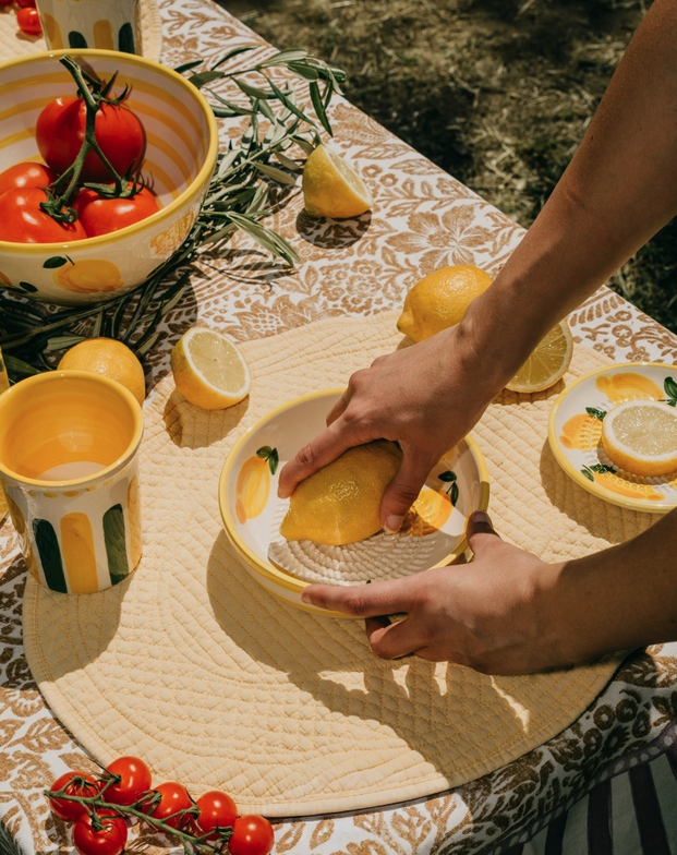 TAÇA RALADOR MÉDIA "LIMONE" ALFAR TIERRA COCIDA Conjunto de loiça cerâmica com motivos de limão e peças amarelas num ambiente de mesa exterior.
