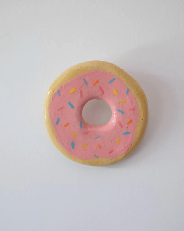 PEÇAS DE CERÂMICA "BREAKFAST FOR DINNER" KIKA Donut decorativo com cobertura rosa e granulado colorido sobre fundo branco