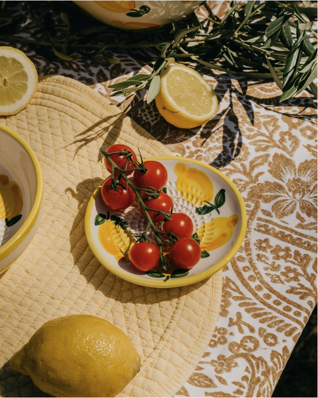 PRATO RALADOR PEQUENO "AMARELO E BRANCO- LIMÃO" ALFAR TIERRA COCIDA Prato de cerâmica com tomates e limões sobre tecido acolchoado e toalha decorada.