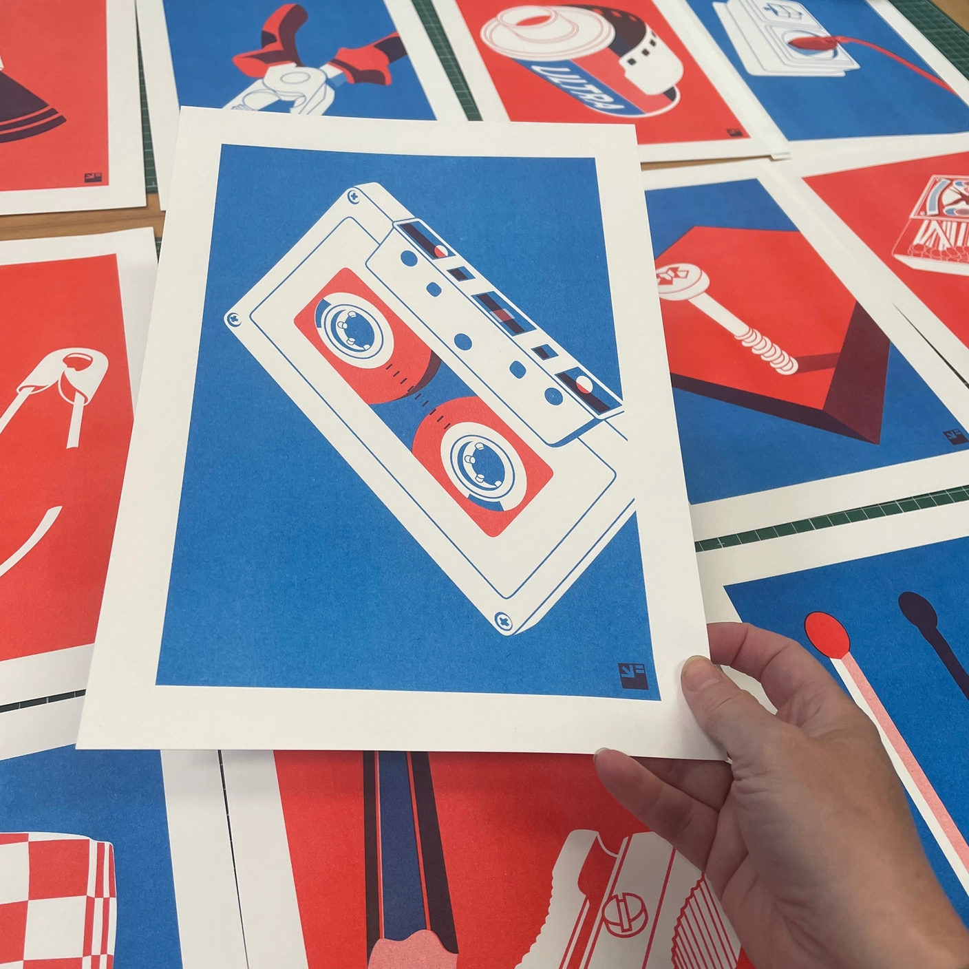 RISO PRINT - FITA CASSETE DE ÁUDIO - EXTRA ORDINARY - A4 VRIJFORMAAT Várias impressões em papel com ilustrações coloridas em azul, branco e vermelho de objetos variados.