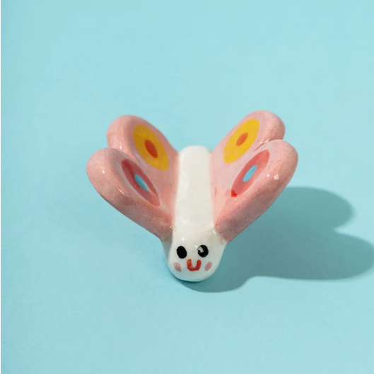 PEÇA EM CERÂMICA "LETA, THE BUTTERFLY" ANA SEIXAS Figura decorativa em cerâmica em forma de borboleta com asas coloridas e rosto sorridente