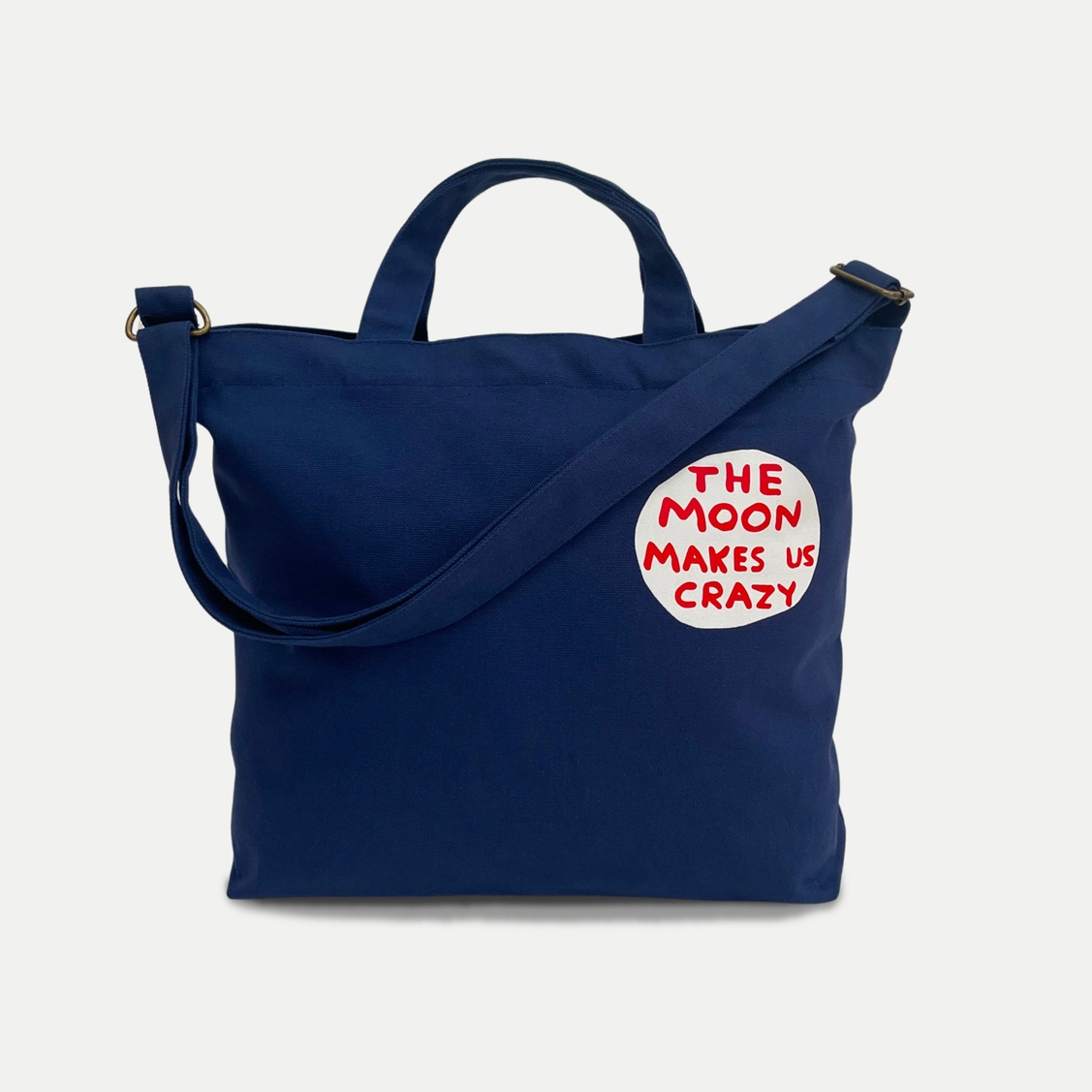 BOLSA "THE MOON MAKES US CRAZY" - DAVID SHRIGLEY Mala azul escuro com texto estampado
