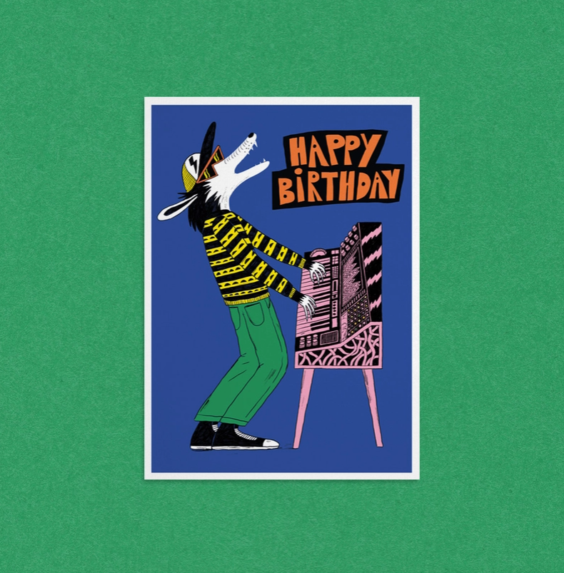 POSTAL "HAPPY BIRTHDAY" DANS LES DENTS Cartão de aniversário ilustrado com lobo a tocar teclado e texto HAPPY BIRTHDAY