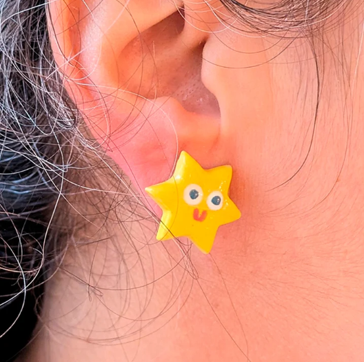 BRINCOS "STAR" ANA SEIXAS Brinco amarelo em forma de estrela com rosto sorridente na orelha