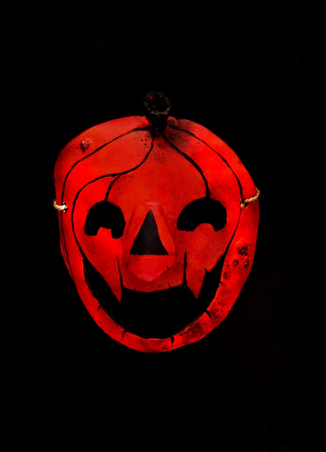 MÁSCARA "COCA" ANDREIA PINHO Máscara vermelha de abóbora para decoração com fundo preto