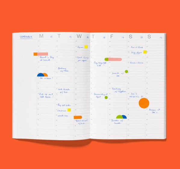PLANNER A5 "UNDATED" VERMELHO MISHMASH Agenda semanal aberta com várias anotações manuscritas e marcadores coloridos sobre fundo laranja.