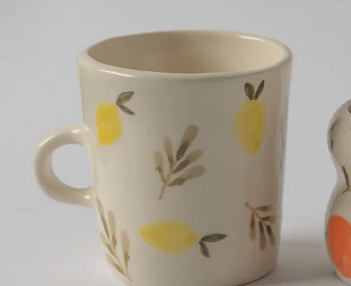 CHÁVENA ALTA COM ALÇA CITRUS MANU SOUZA Caneca de cerâmica com desenho de limões e folhas em fundo branco