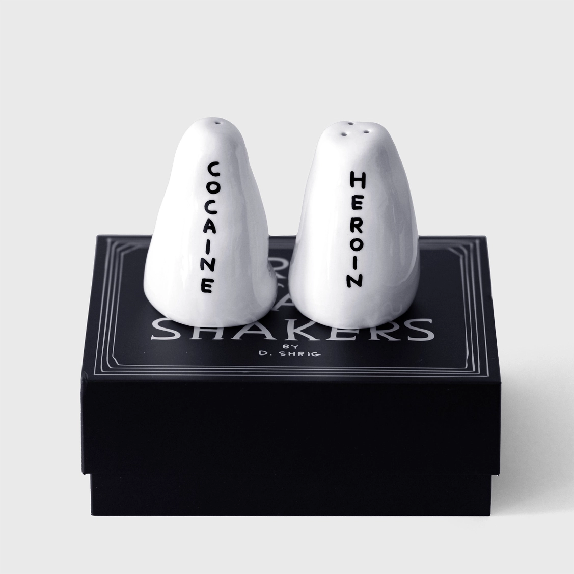 SALEIRO/PIMENTEIRO "COCAINE, HEROIN" - DAVID SHRIGLEY Conjunto de saleiros e pimenteiros brancos com inscrições em caixa preta.