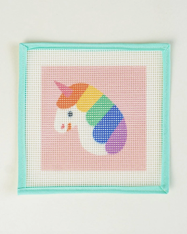 "RAINBOW UNICORN ORNAMENT KIT" UNWIND STUDIO Painel de bordado com desenho de unicórnio colorido em fundo rosa e moldura azul claro