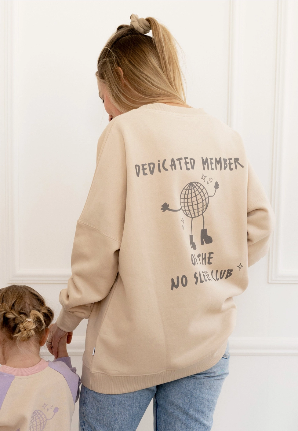 SWEAT ADULTO NO SLEEP CLUB BEGE LILIPUT Pessoa de costas a usar sweatshirt bege com texto e desenho cinzento