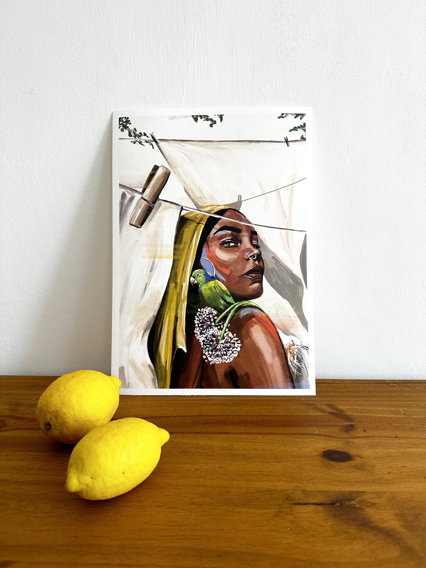 COLETIVA BEST OFF 2024 "JÚLIA" ISA MARITA Quadro com pintura de mulher e ave verde com limões amarelos em superfície de madeira