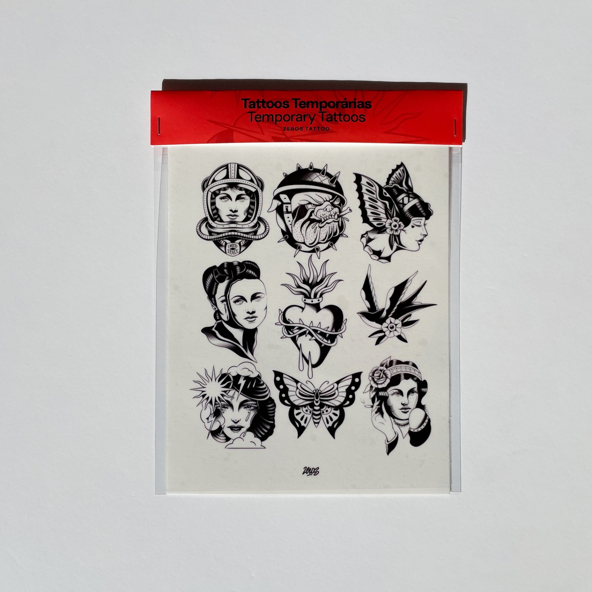TATUAGENS TEMPORÁRIAS - PRETO E BRANCO ZEROS TATTOO Pacote de tatuagens temporárias com vários desenhos a preto e branco em fundo branco e embalagem vermelha.